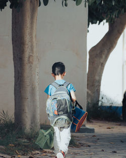 Rear view of boy standing against wall