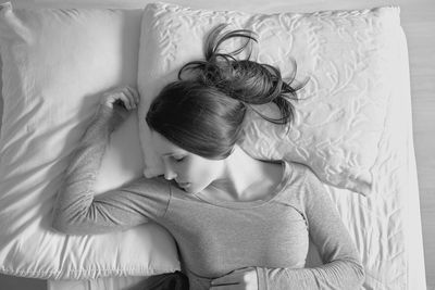 Directly above shot of young woman sleeping on bed at home