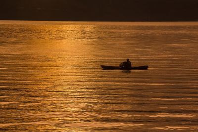Silhouette boat sailing in lake against sky during sunset