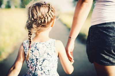 Rear view of daughter holding hand of mother