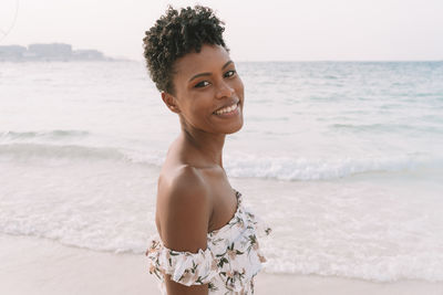 Portrait of smiling young woman standing on beach