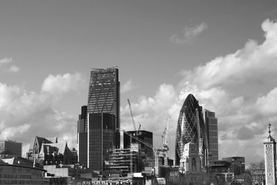 Directly below shot of modern buildings against cloudy sky