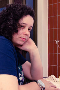 Portrait of woman with hand on chin sitting at home