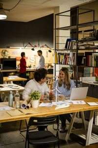 Coworkers working in office with wind turbine model on desk