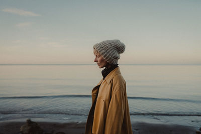 Close-up of young woman standing at beach against sky