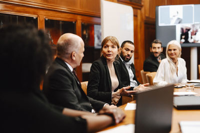 Businesswoman discussing strategy with financial advisors in board room during conference meeting