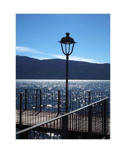 Street light by sea against clear sky