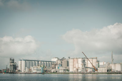 Silos by pier against sky