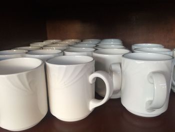Close-up of mugs on shelf