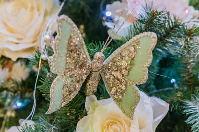 Close up of christmas tree decorated with butterfly and tender pink flower.