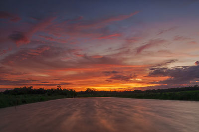 Scenic view of landscape against dramatic sky during sunset