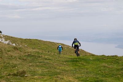 Rear view of people riding bicycles on mountain