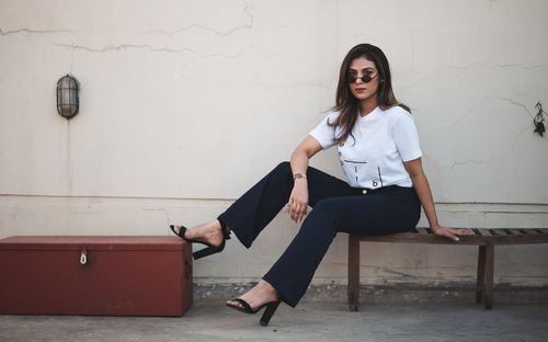 Portrait of woman sitting against wall