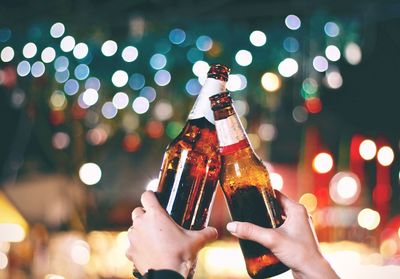 Close-up of hand holding wine bottles against blurred background