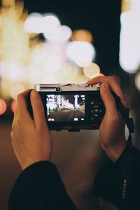 Cropped image of woman photographing through camera at night