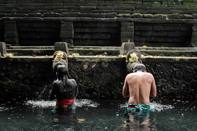 Rear view of people praying in water