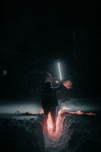 Rear view of man standing by bonfire at night