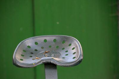 Close-up of metallic seat against green wall