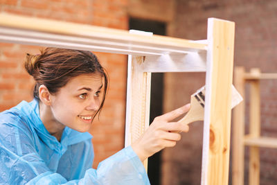 Side view of young woman standing in cage