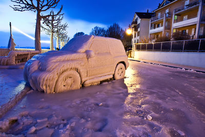 Snow covered vehicle by bare trees