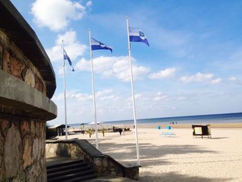 Flags at beach against sky