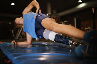 Full length of man with prosthetic legs exercising in gym