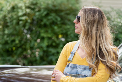 Beautiful woman looking away while standing by car