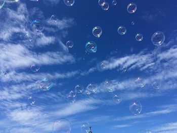 Low angle view of bubbles against blue sky