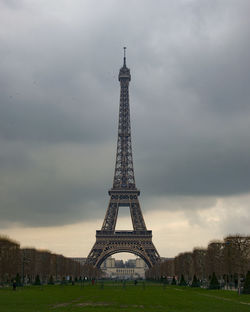 Communications tower in city against cloudy sky
