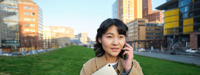 Portrait of young woman standing in city