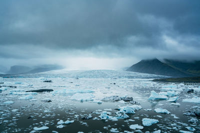 Scenic view of ice glacier against cloudy sky