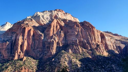 Low angle view of rocky mountains against clear sky