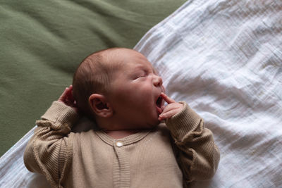 Portrait of cute baby boy lying on bed at home