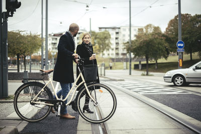 Business people with bicycle crossing city street