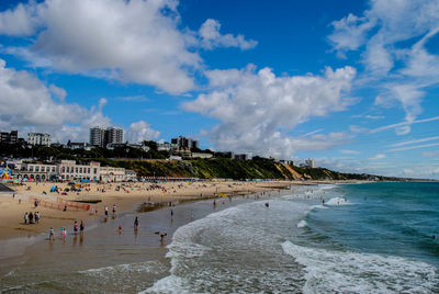 People at beach against cloudy sky