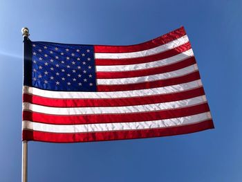 Low angle view of flag against clear blue sky