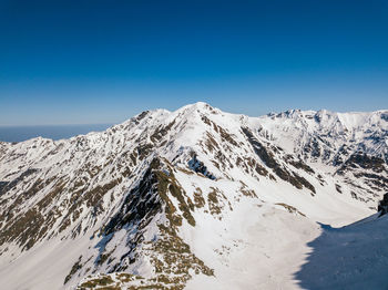 Scenic view of snowcapped mountains against clear blue sky