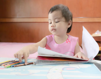 Cute girl playing wit h colored pencils at table