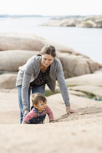 Happy mother with baby girl at beach on sunny day