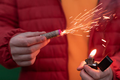 Low angle view of hand holding burning outdoors