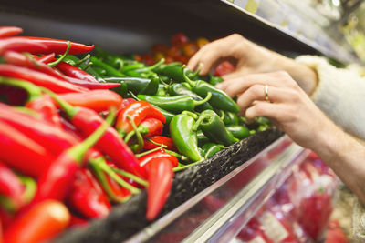 Cropped image of man buying chili peppers at supermarket