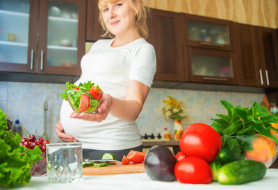 Pregnant woman holding salad bowl