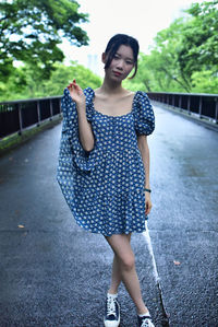 Portrait of smiling young woman standing on road