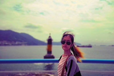 Portrait of woman standing by sea against sky