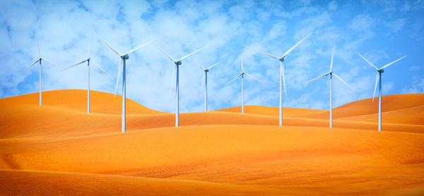 Wind turbines on land against sky