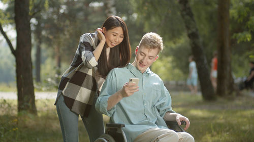 Man on wheelchair taking selfie with girlfriend at park