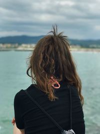Rear view of woman standing against sea
