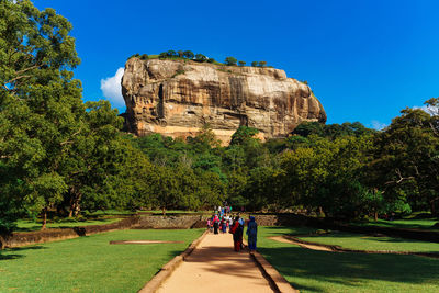 People on rock formations against blue sky