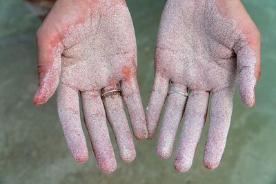 Close-up of cropped hands with sand