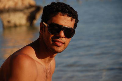 Close-up portrait of smiling young man standing against sea